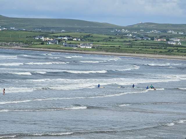 mushy waves all along the beach with a few beginner surfers in the shallows